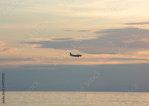 the silhouette of an airplane against the background of the sea and the setting sun.