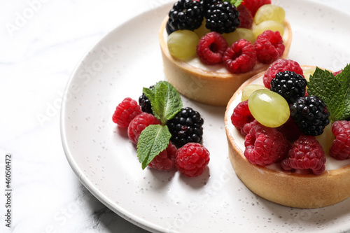 Delicious tartlets with berries on table, closeup