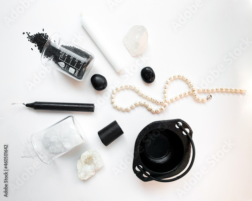 Collection of white and black witchy items (candles, crystals, pearls, stones, salts, cauldron) isolated on a white background 