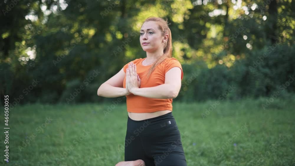 Young woman in sportswear practices yoga in nature.