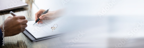 Businessman Signing Contract With Keys On It