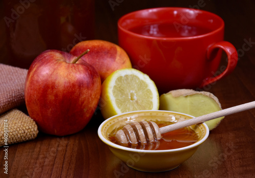 Autumn still life with honey, apples, ginger and a cup of tea stock images. Bowl of honey with a dipper, lemon, red apples and ginger on the table stock photo. Healthy food when sick images