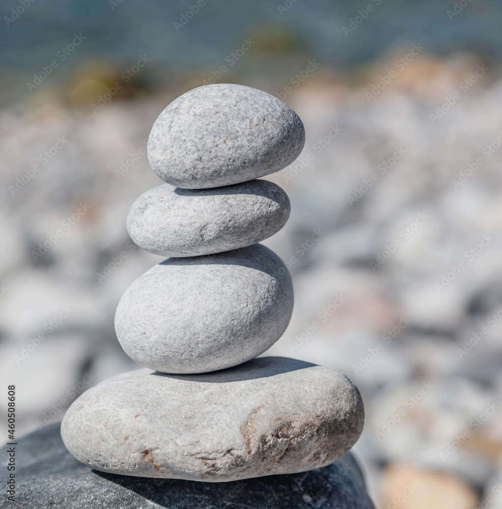Zen balance stones, smooth pebbles pyramid stacked on blue background.