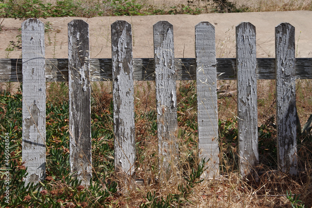Close-up view of a segment of an old weathered white picket fence