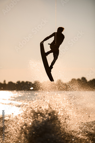 beautiful silhouette of wakeboarder athlete man jumping high making tricks in the air © fesenko