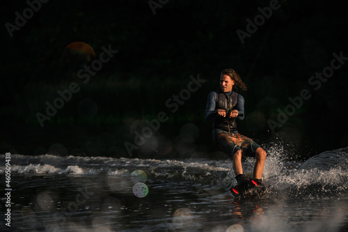 Fototapeta Naklejka Na Ścianę i Meble -  wet man in wetsuit energetically balancing on water surface on wakeboard