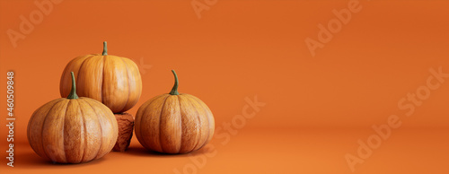 Three Pumpkins on a Orange colored background. Autumn themed Banner with copy-space.