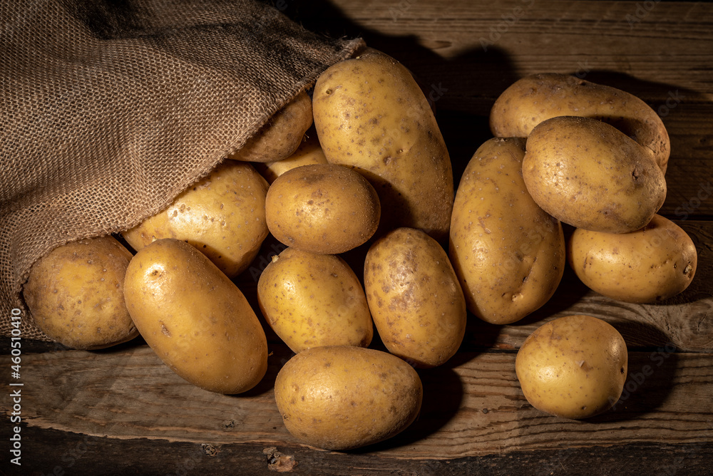 Harvest potatoes in burlap sack on rustic background Harvest potatoes in burlap sack on rustic background