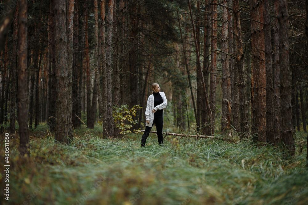 woman in white sweater walking through the woods woman in white sweater walking through the woods