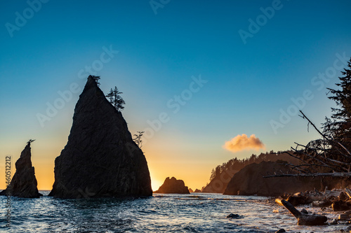 dramatic sunset in Rialto beach in Olympic National Park in Washington state. waves from the pacific crashes on the sea stacks and massive logs on the seashore.