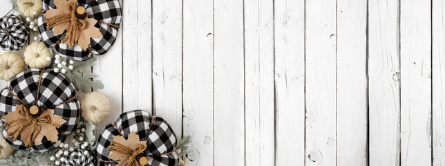 Modern farmhouse autumn corner border over a white wood banner background. Black and white buffalo plaid pumpkins, leaves and berries. Above view with copy space.