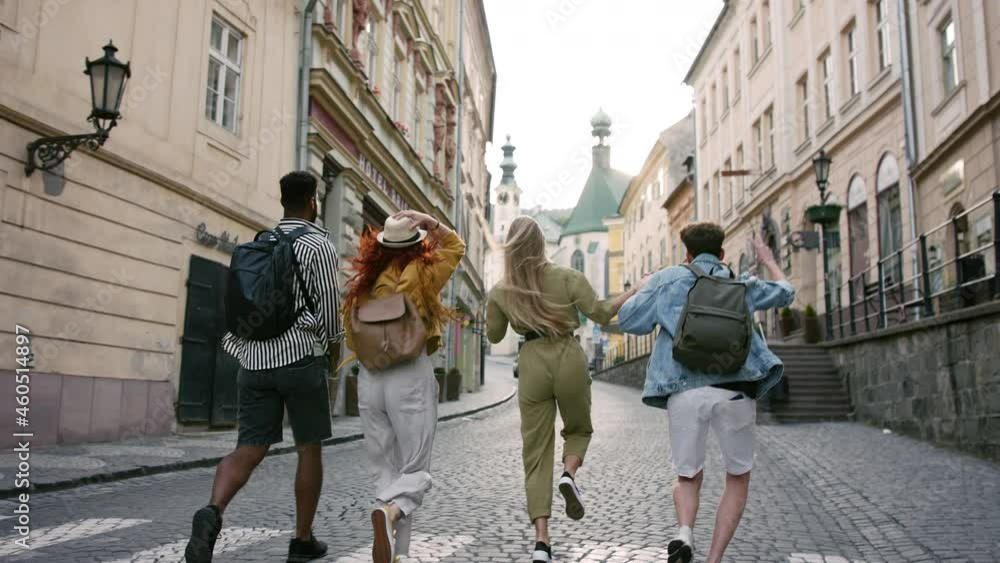 Rear view of group of young people outdoors on trip in town, running, jumping and holding hands. Rear view of group of young people outdoors on trip in town, running, jumping and holding hands.
