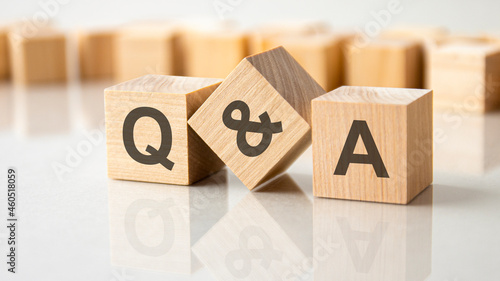 three wooden cubes with the letters Q and A on the bright surface of a gray table, business concept photo