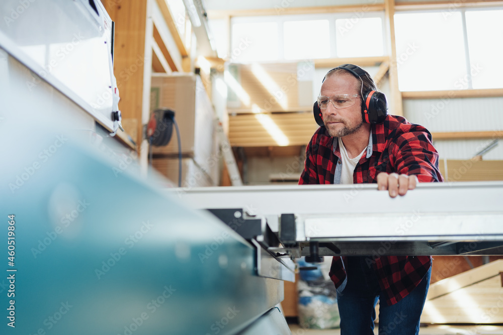 Obraz premium Carpenter or joiner in a factory working with machinery