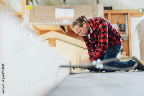 Carpenter working kneeling down on a timber frame