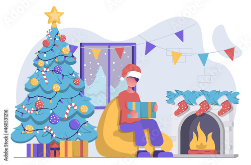 А man opens Christmas present by the fireplace and the Christmas tree