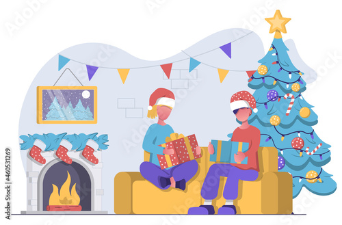 A man and woman sit on couch next to fireplace and Christmas tree and open Christmas presents