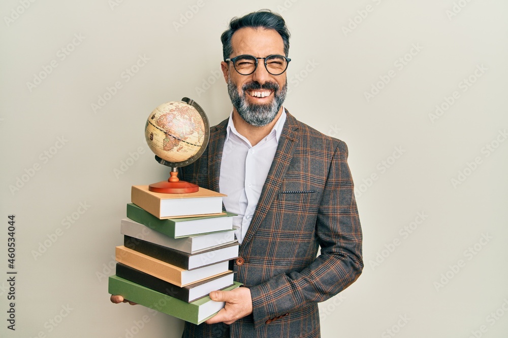 Middle age man with beard and grey hair teacher holding vintage world ball smiling and laughing hard out loud because funny crazy joke. Middle age man with beard and grey hair teacher holding vintage world ball smiling and laughing hard out loud because funny crazy joke.