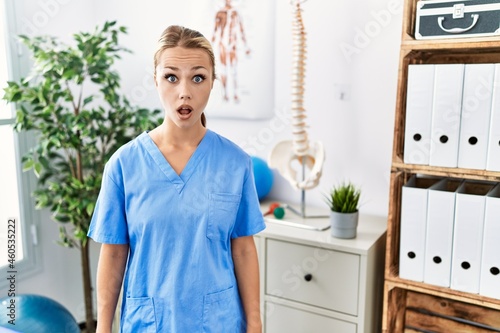 Young caucasian woman working at pain recovery clinic afraid and shocked with surprise expression  fear and excited face.