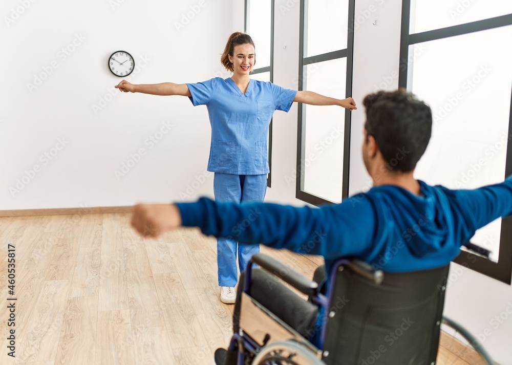 Young disabled man making mobility exercise sitting on wheelchair at the clinic. Young disabled man making mobility exercise sitting on wheelchair at the clinic.