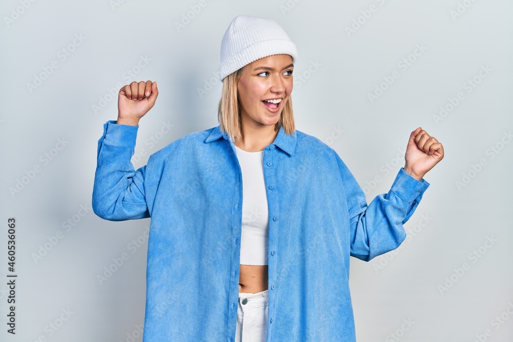 Beautiful blonde woman wearing wool hat dancing happy and cheerful, smiling moving casual and confident listening to music Beautiful blonde woman wearing wool hat dancing happy and cheerful, smiling moving casual and confident listening to music