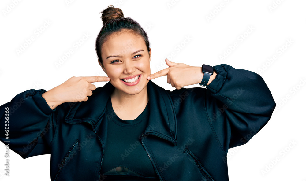 Young hispanic girl wearing sportswear smiling cheerful showing and pointing with fingers teeth and mouth. dental health concept.