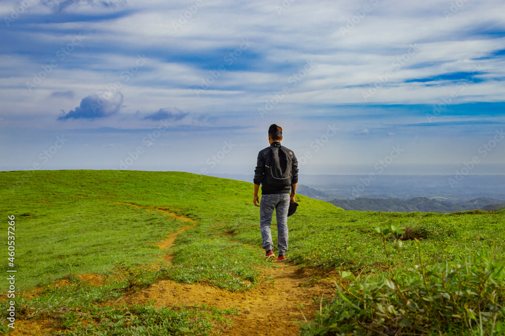 A backpacker walking on a hill with blue sky and copy space, man backpacking on a hill and blue sky background with copy space, successful man concept.