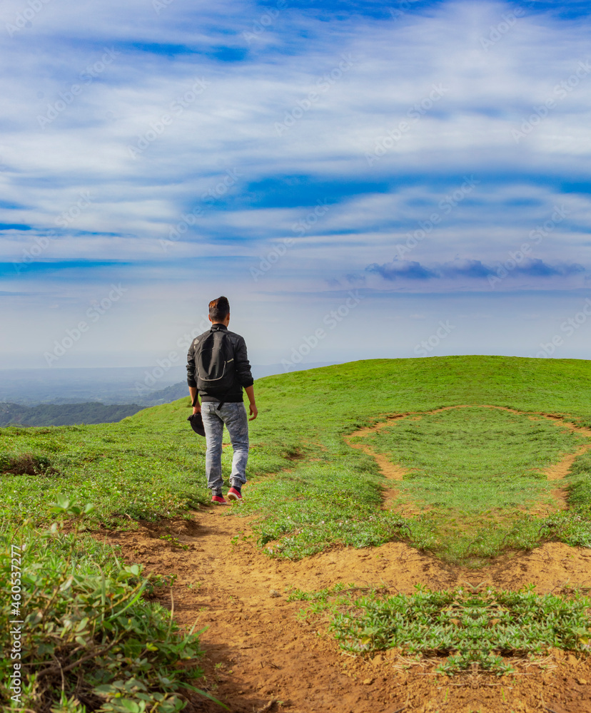 A backpacker walking on a hill with blue sky and copy space, man backpacking on a hill and blue sky background with copy space, successful man concept.