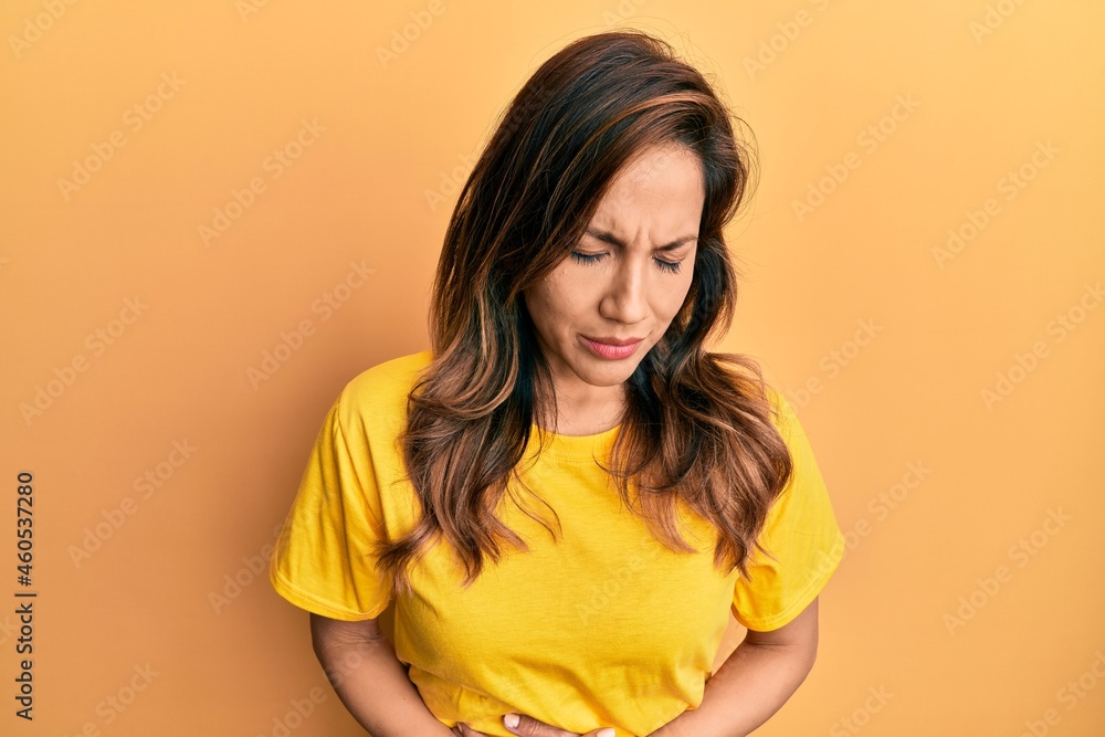 Obraz premium Young latin woman wearing casual clothes with hand on stomach because indigestion, painful illness feeling unwell. ache concept.