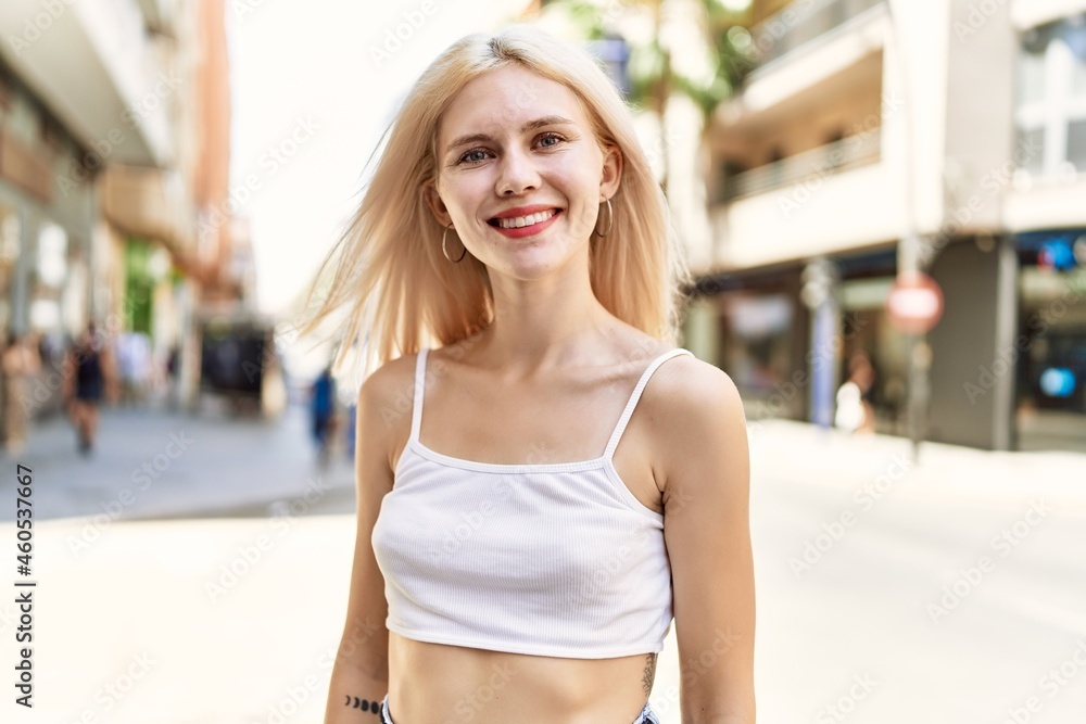 Young blonde girl smiling happy standing at the city.