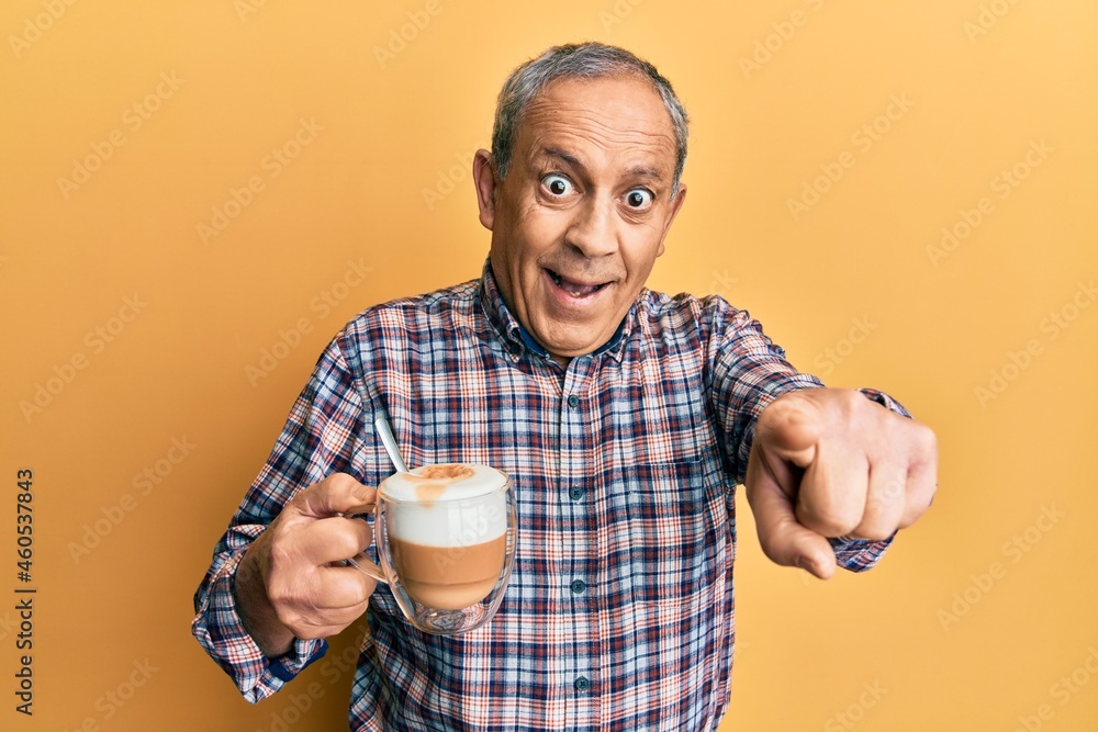 Handsome senior man with grey hair drinking a cup coffee pointing to you and the camera with fingers, smiling positive and cheerful Handsome senior man with grey hair drinking a cup coffee pointing to you and the camera with fingers, smiling positive and cheerful