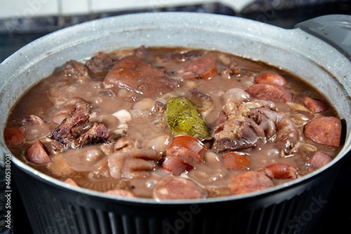 Traditional Brazilian feijoada in a rustic pan with details on the ingredients