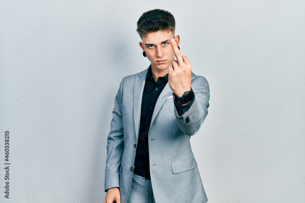 Young caucasian boy with ears dilation wearing business jacket showing middle finger, impolite and rude fuck off expression Young caucasian boy with ears dilation wearing business jacket showing middle finger, impolite and rude fuck off expression