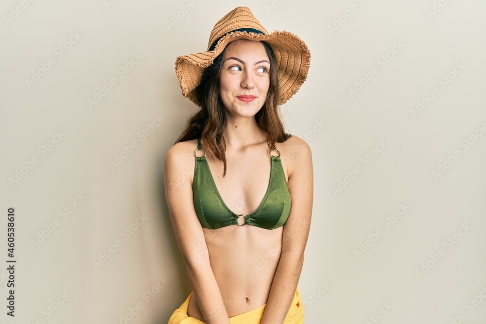 Young brunette woman wearing bikini smiling looking to the side and staring away thinking. Young brunette woman wearing bikini smiling looking to the side and staring away thinking.
