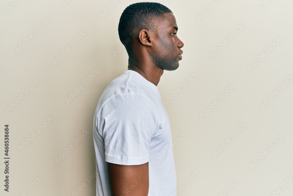 Young african american man wearing casual white t shirt looking to side, relax profile pose with natural face with confident smile. Young african american man wearing casual white t shirt looking to side, relax profile pose with natural face with confident smile.