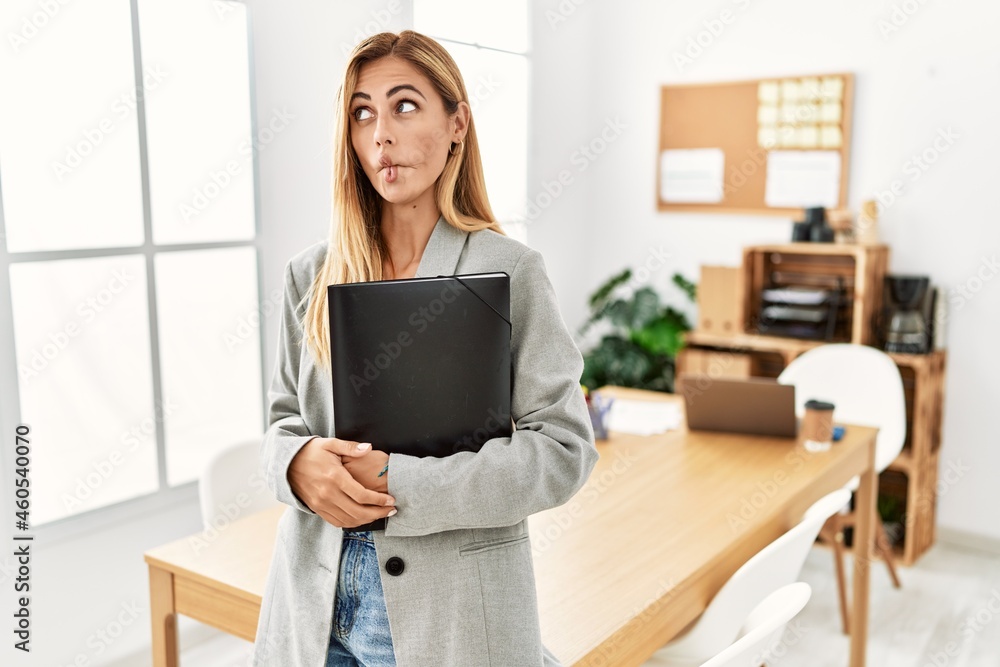 Blonde business woman at the office making fish face with lips, crazy and comical gesture. funny expression. Blonde business woman at the office making fish face with lips, crazy and comical gesture. funny expression.