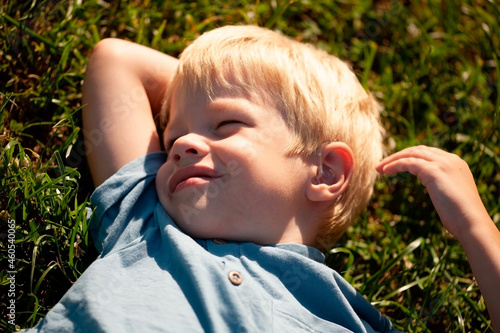 Little beautiful kid outdoor. Lay on green grass.