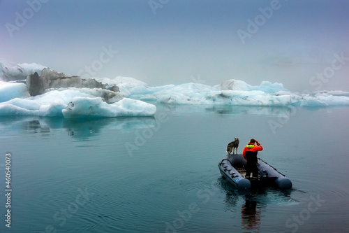 A rescue staff with a rescue dog riding a rubber patrol boat in the frigid waters and ice beg laden  of Glacier lagoon , Jokulsarlon ,Iceland.