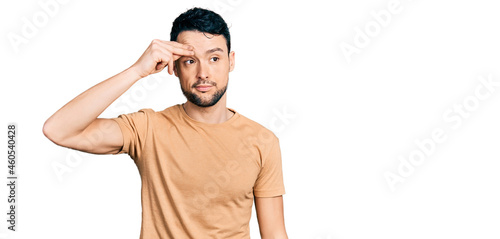 Hispanic man with beard wearing casual t shirt worried and stressed about a problem with hand on forehead, nervous and anxious for crisis