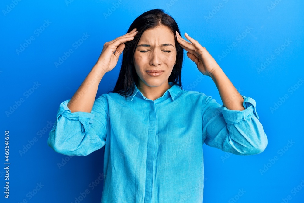 Young latin woman wearing casual clothes with hand on head, headache because stress. suffering migraine. Young latin woman wearing casual clothes with hand on head, headache because stress. suffering migraine.