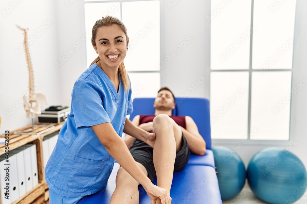 Young hispanic physioterapist woman make ankle rehab treatment to man at the clinic. Young hispanic physioterapist woman make ankle rehab treatment to man at the clinic.
