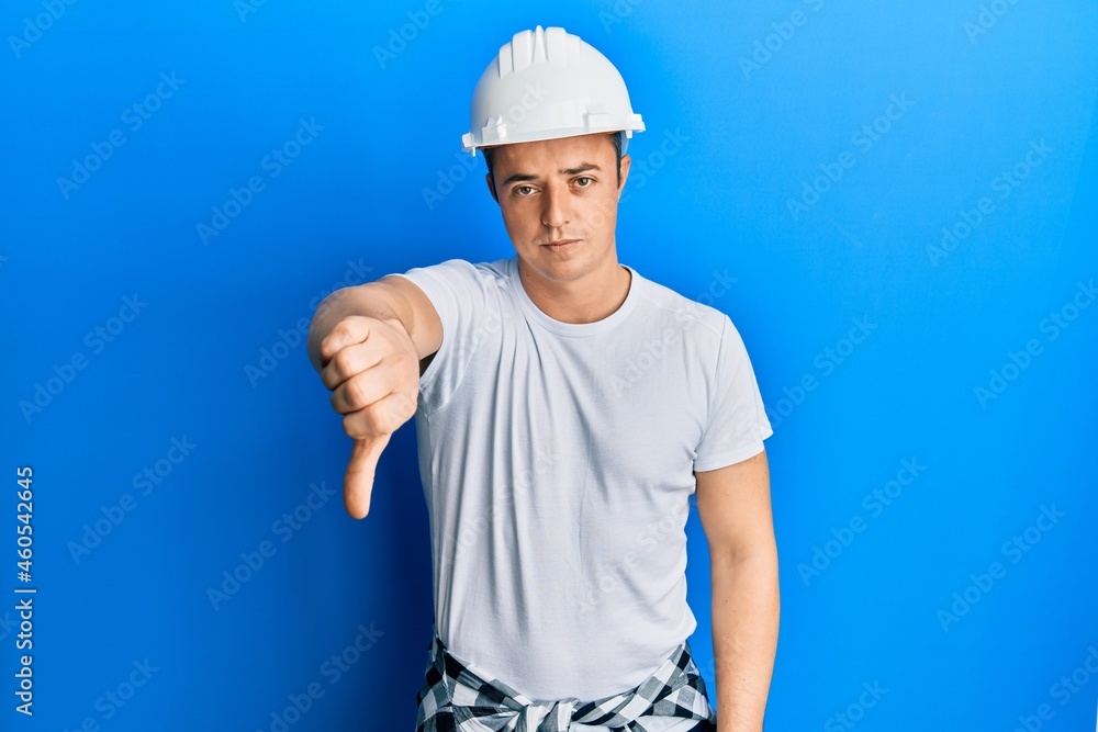 Handsome young man wearing builder uniform and hardhat looking unhappy and angry showing rejection and negative with thumbs down gesture. bad expression. Handsome young man wearing builder uniform and hardhat looking unhappy and angry showing rejection and negative with thumbs down gesture. bad expression.