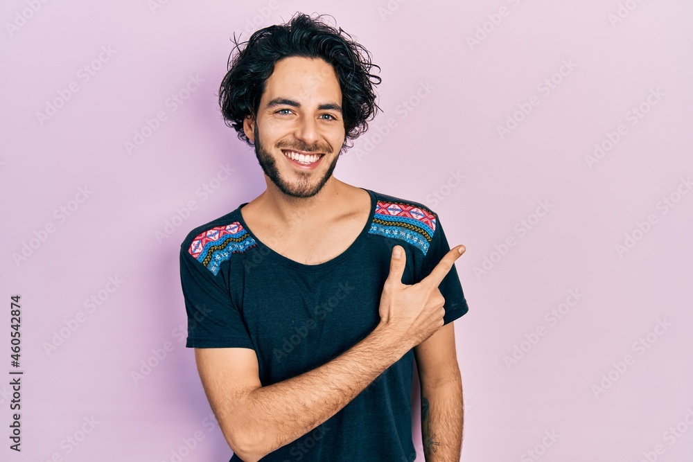 Handsome hispanic man wearing casual t shirt smiling cheerful pointing with hand and finger up to the side Handsome hispanic man wearing casual t shirt smiling cheerful pointing with hand and finger up to the side