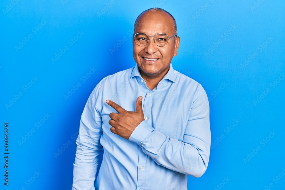 Middle age latin man wearing casual clothes and glasses cheerful with a smile of face pointing with hand and finger up to the side with happy and natural expression on face Middle age latin man wearing casual clothes and glasses cheerful with a smile of face pointing with hand and finger up to the side with happy and natural expression on face