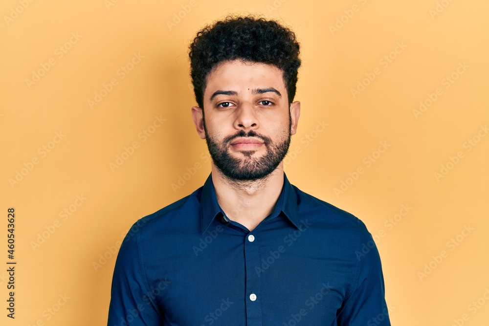 Fototapeta premium Young arab man with beard wearing casual shirt relaxed with serious expression on face. simple and natural looking at the camera.