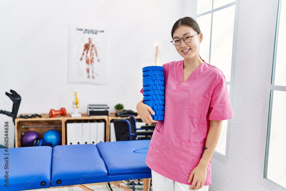 Young asian woman holding rehabilitation roller at physiotherapy clinic