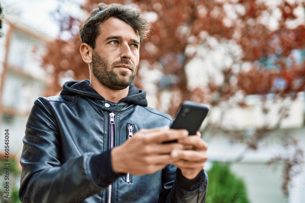 Handsome hispanic man with beard with serious face outdoors using smartphone Handsome hispanic man with beard with serious face outdoors using smartphone