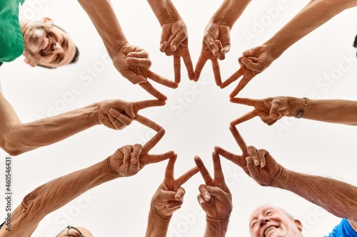 Group of middle age friends doing victory sign with fingers and hands together.