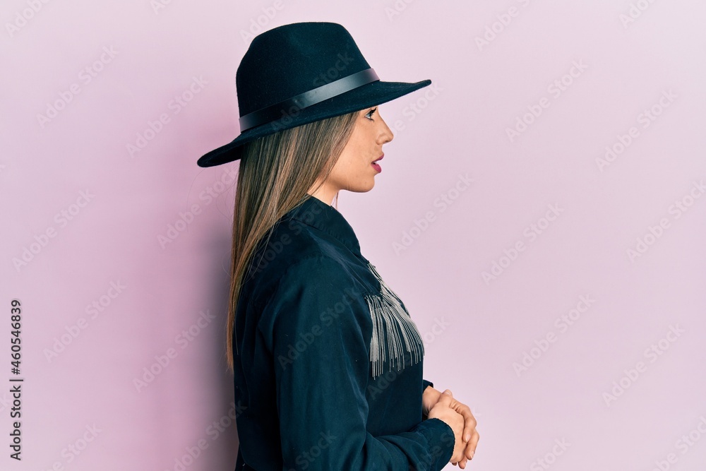 Young hispanic woman wearing cowgirl style looking to side, relax profile pose with natural face with confident smile. Young hispanic woman wearing cowgirl style looking to side, relax profile pose with natural face with confident smile.