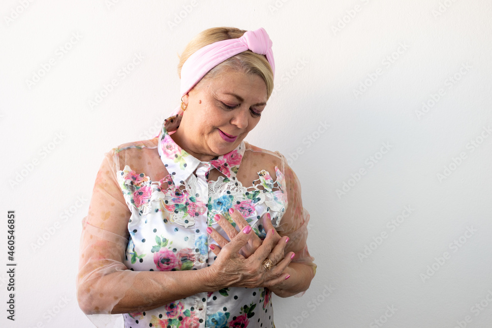breast cancer, elderly woman with hands on chest smiling looking down, pink october. breast cancer, elderly woman with hands on chest smiling looking down, pink october.